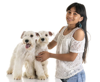 Portrait of woman with dog standing against white background
