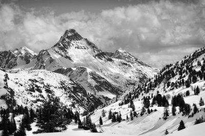 Scenic view of snow covered mountains against cloudy sky