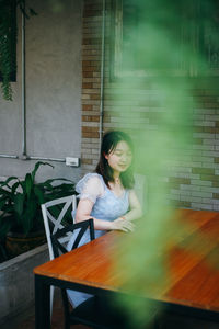 Portrait of young woman sitting on table