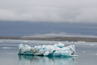 Ice floating on sea against sky during winter