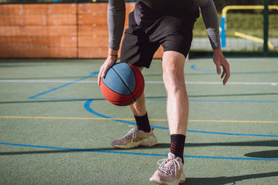 Boy practices dribbling basketball under his feet and improves his hand, body and foot coordination