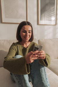 Portrait of young woman sitting on sofa at home