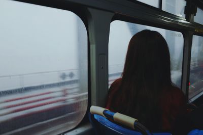 Rear view of woman sitting in bus during rain