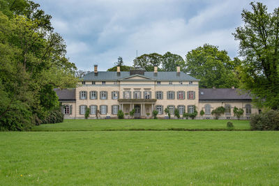 Lawn by house on field against sky