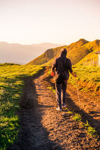 Rear view of man standing on mountain against sky