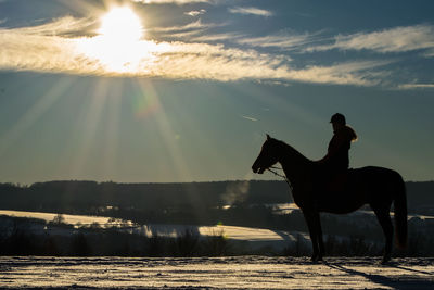 Silhouette man on horse against sky