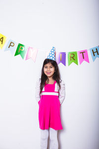 Portrait of a smiling young woman standing against the wall