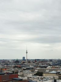 Communications tower and cityscape against sky