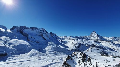 Scenic view of snowcapped mountains against clear blue sky