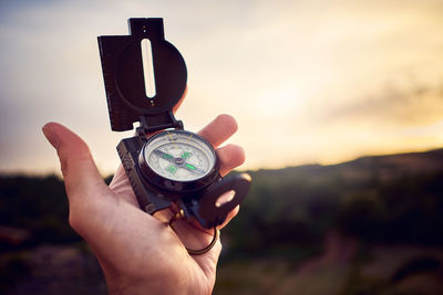 Close-up of hand holding camera against sky