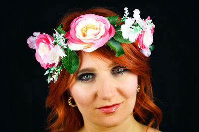 Close-up of young woman with bouquet against black background