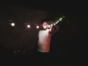 Young man standing in illuminated dark room