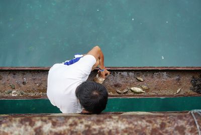 High angle view of man crouching on metal