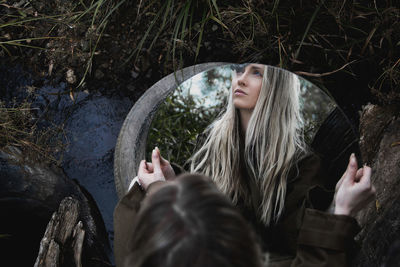 A woman is reflected in a round mirror in nature