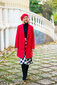 Portrait of young woman standing on footpath