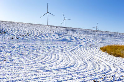 Wind turbines in a snow covered field with blue sky