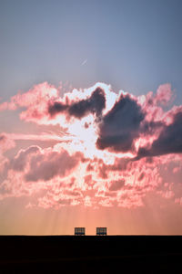 Low angle view of silhouette building against dramatic sky