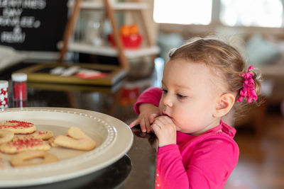 Cute girl looking at cookies in plate