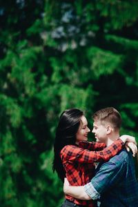 Side view of young couple standing face to face in forest