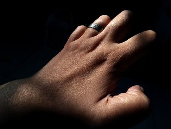Cropped hand of woman wearing ring against black background