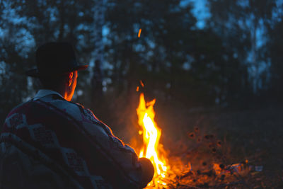 Rear view of man with bonfire in forest