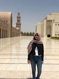 Full length portrait of woman standing against building