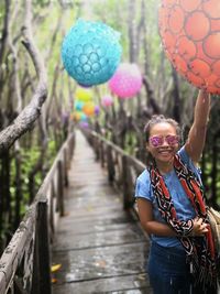 Smiling young woman standing by balloons on boardwalk