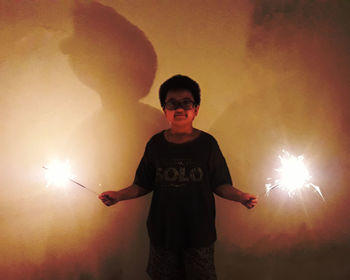 Man with arms outstretched standing against illuminated lamp