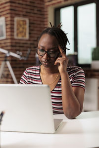 Young woman using laptop while sitting on table