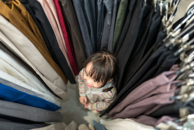 High angle view of girl standing amidst clothes rack