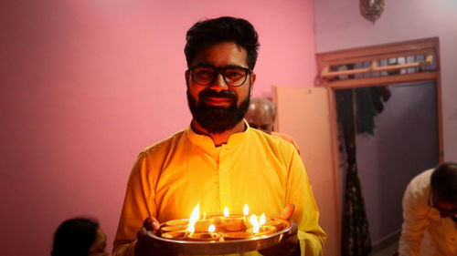 Portrait of man holding lit diya at home