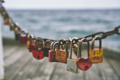 Close-up of padlocks hanging on railing against sea