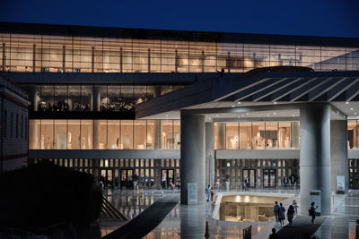 People in illuminated modern building at night