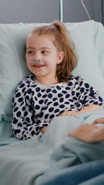 Smiling girl lying on hospital bed