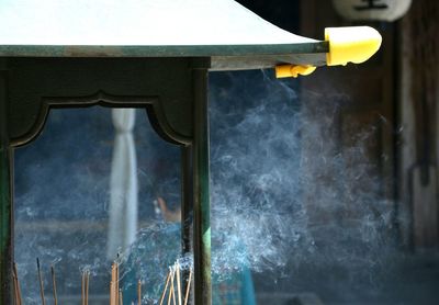 Close-up of smoke emitting from incenses in temple