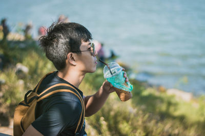 Young man having drink by sea