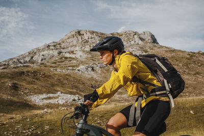 Man riding bicycle on mountain against sky