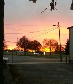 Power lines against sky at sunset