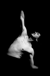 Shirtless man dancing against black background