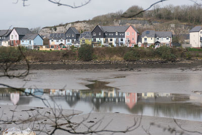 Houses by lake against sky