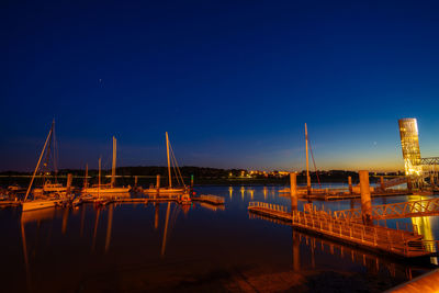 Sailboats moored in sea against clear blue sky at night