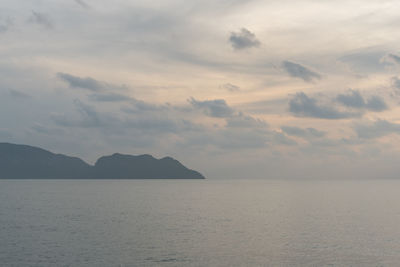 Early morning sea view, spindrift clouds, still waters and a distant mountain on the horizon