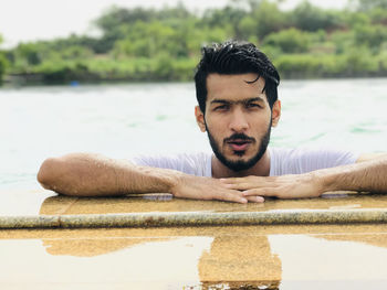 Portrait of handsome wet young man swimming in lake