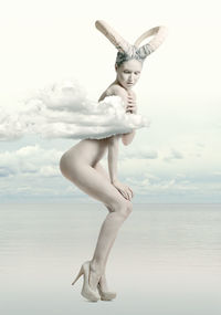 Digitally generated image of sensuous naked woman standing in sea against sky