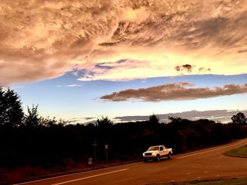 Cars on road against sky during sunset