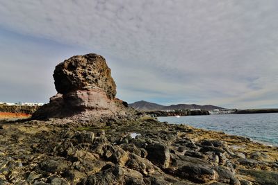 Rock formation by sea against sky