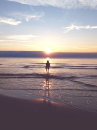 Silhouette man on beach against sky during sunset