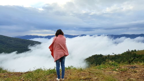 Rear view of woman standing on mountain against sky