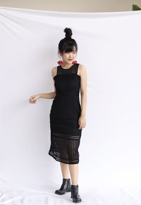 Full length portrait of woman standing against wall