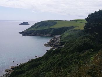 Scenic view of sea by cliff against sky